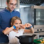 Father and daughter cooking a meal together, enjoying family bonding in a modern kitchen.
