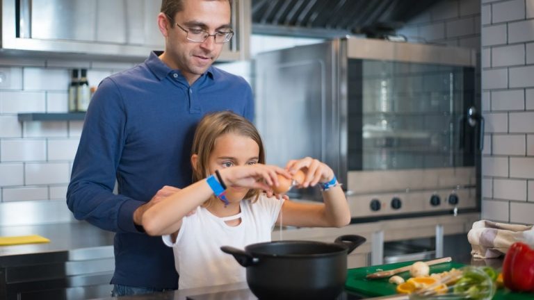 Father and daughter cooking a meal together, enjoying family bonding in a modern kitchen.